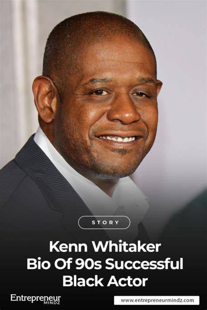 Kenn Whitaker is a black suit, smiling and wearing spectacles. 