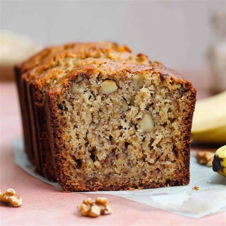 Slice of banana nut bread topped with butter on a grey plate.